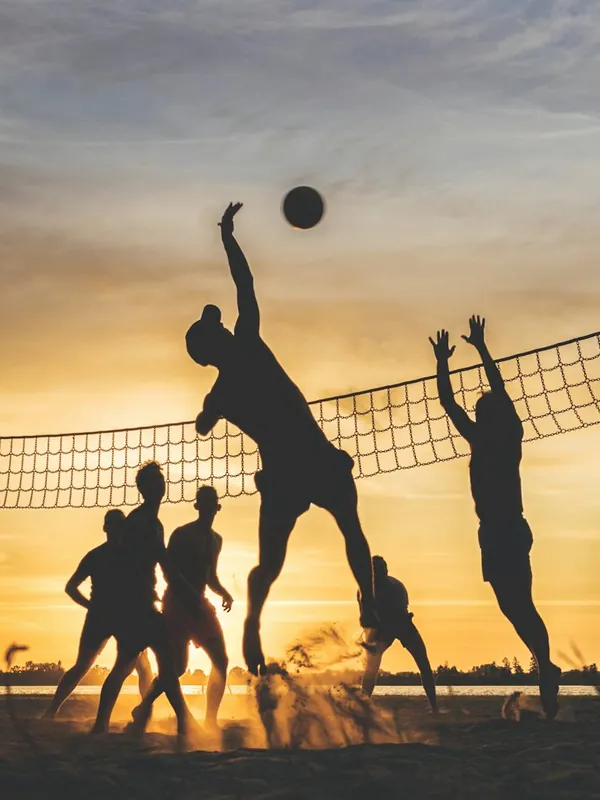 Volleyball players at the net at sunset